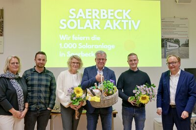 Die Betreiber der 1000. Photovoltaikanlage in der Klimakommune Saerbeck, Niklas Dirksen (2. von rechts) stellvertretend für seine fünfköpfige Familie zusammen mit Simone und Adrian Mühlenkamp (4. und 3. von rechts) und die Gratulanten (von rechts) Bürgermeister Dr. Tobias Lehberg, Martin Sammler (Leiter Stabsstelle Klimaschutz der Gemeindeverwaltung) und Martina Krause-Rakers (Gemeindeverwaltung).