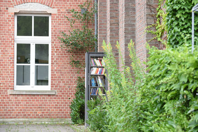 Der offene Bücherschrank für alle steht auf dem Dorfplatz im Eck von köb Bücherei und Pfarrheim St. Georg.